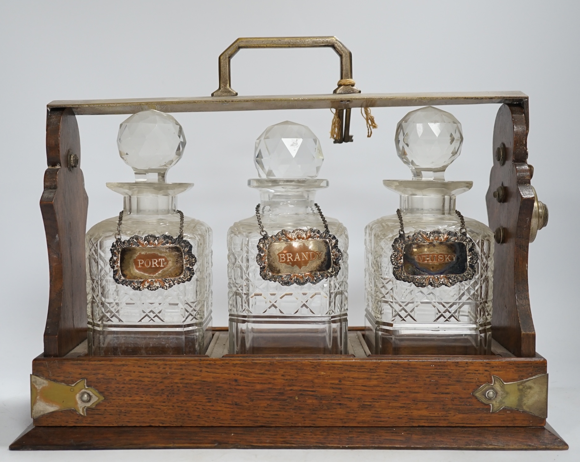 An oak three bottle electroplate tantalus, 29.5cm high